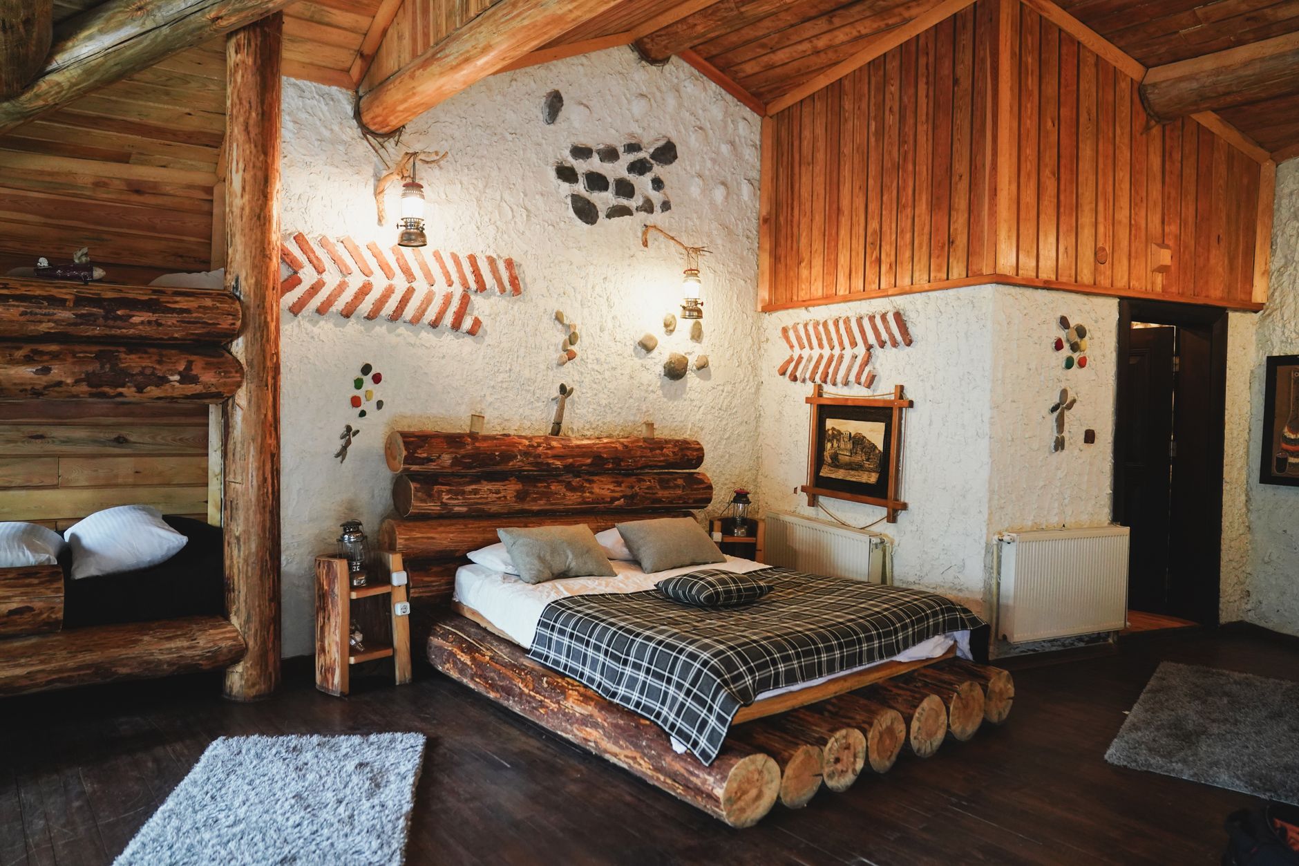 Interior primitor de pensiune montană, cu mobilier din lemn, textile tradiționale și fereastră spre brazi